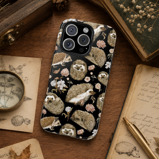 Phone case with hedgehog and floral pattern on a wooden surface with books and magnifying glass.