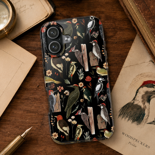 Phone case with nature-themed design on a wooden surface with books and a pen.