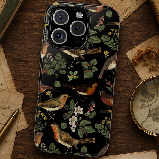 Phone case with nature-themed design featuring robin birds and flowers on a wooden surface with vintage books and papers.
