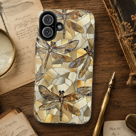 Phone case with dragonfly design on a wooden surface with books and a pen.