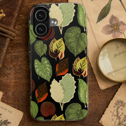 Phone case with leaf pattern on a wooden surface with vintage books and papers.