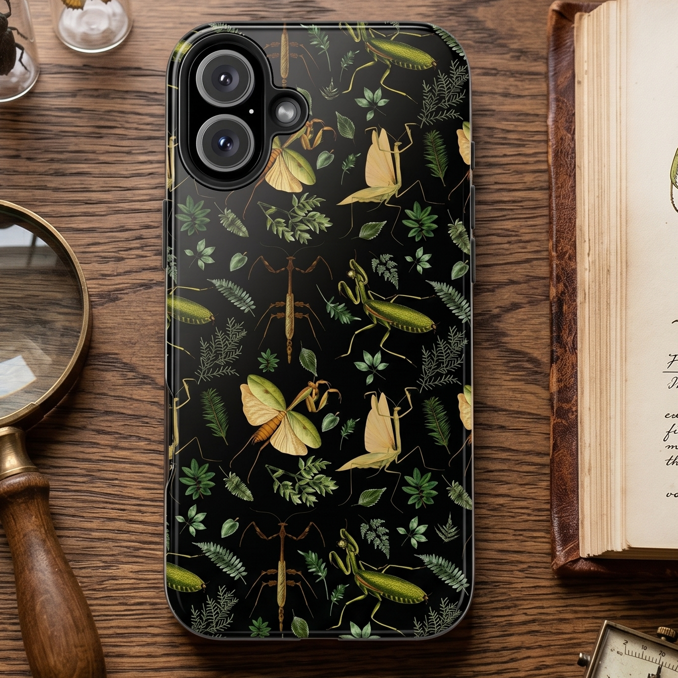 Phone case with praying mantis design on a wooden table with books and magnifying glass