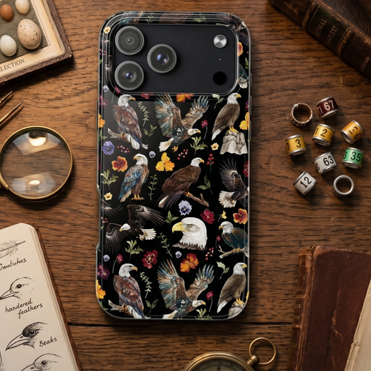 Phone case with eagle and floral design on a wooden surface with books and dice.