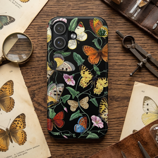 Phone case with butterfly design on a wooden table with vintage books and tools
